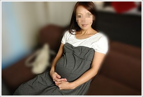 ソファーに座りこちらを見つめる着衣の妊婦